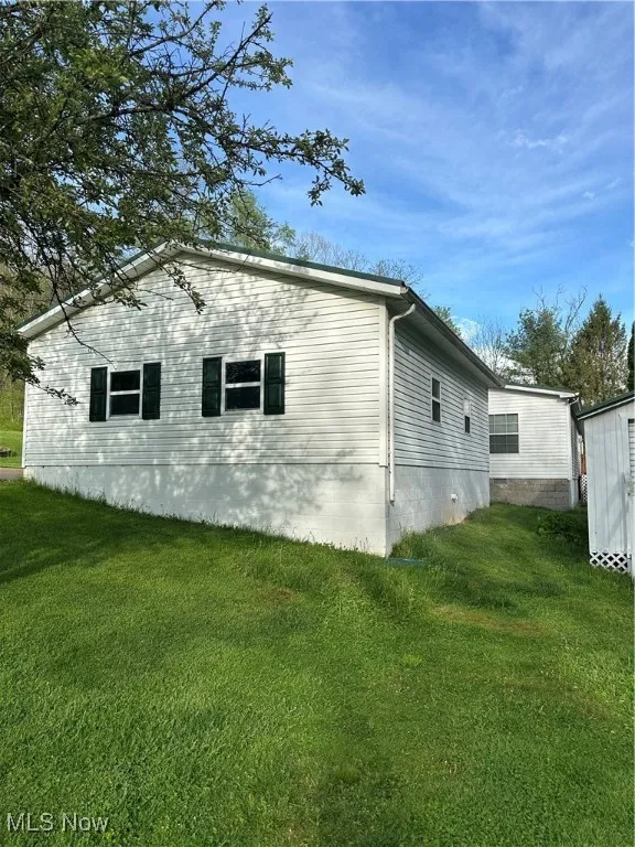 View of home's exterior with a lawn and a storage unit