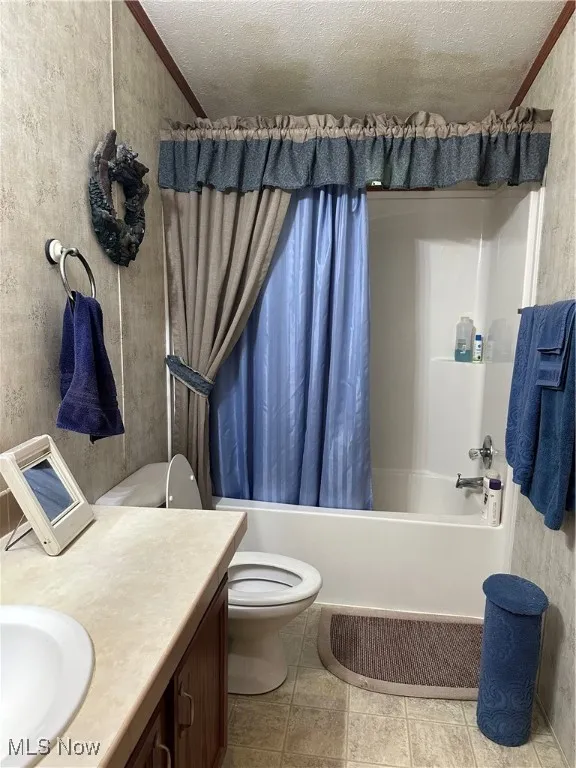Bathroom with shower / bath combination with curtain, toilet, vanity, a textured ceiling, and ornamental molding