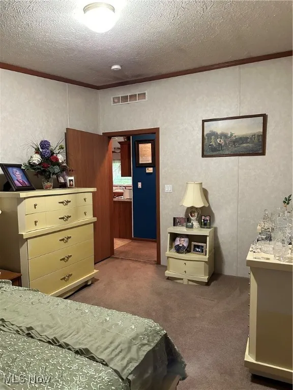Carpeted bedroom featuring a textured ceiling and ornamental molding
