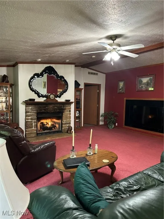 Living room featuring a fireplace, carpet floors, a textured ceiling, a ceiling fan, and vaulted ceiling