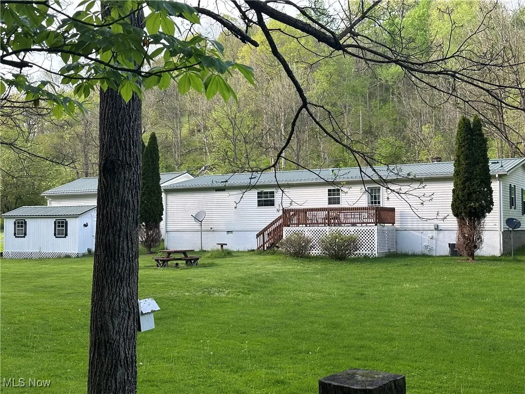 View of yard with a deck and a view of trees