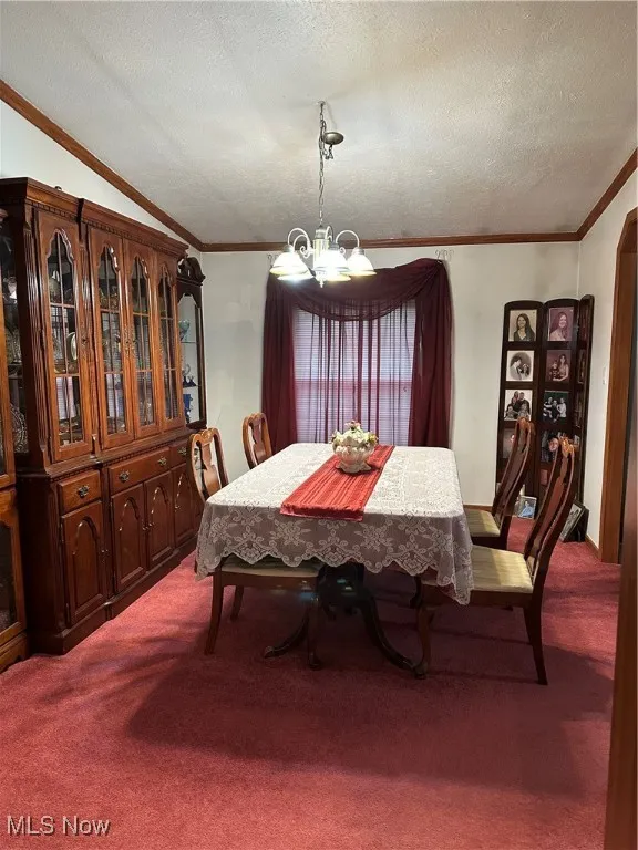 Dining area with a chandelier, crown molding, a textured ceiling, carpet, and lofted ceiling