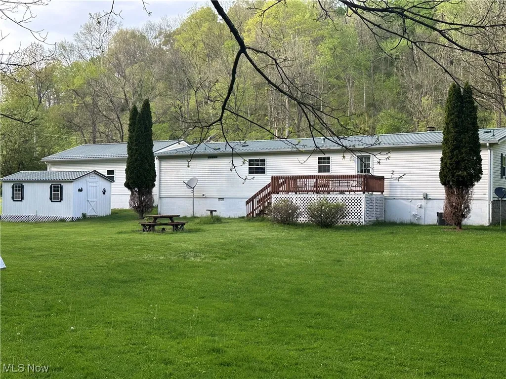 Rear view of house featuring a yard, a deck, metal roof, and crawl space