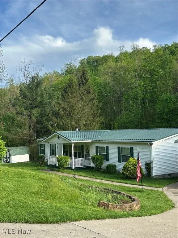 Ranch-style home featuring covered porch, metal roof, a chimney, and a front yard