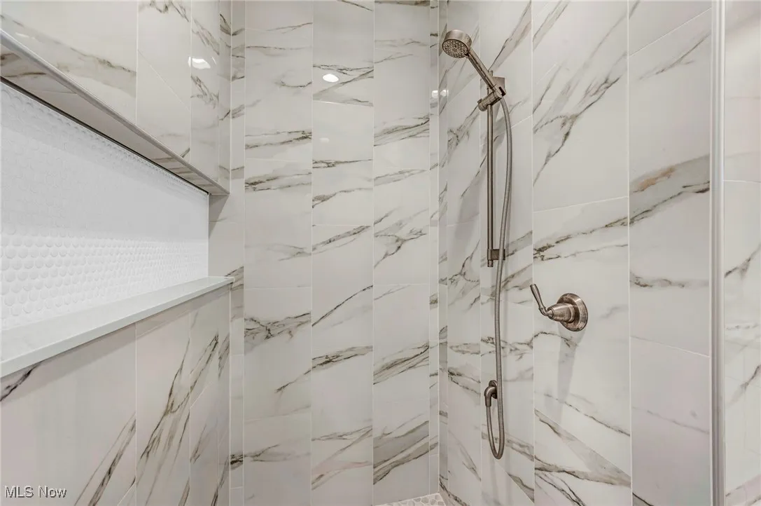 Full bath with a marble finish shower