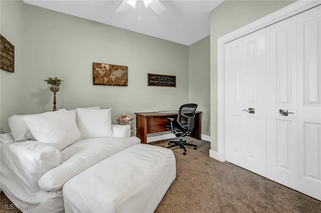 Carpeted home office with ceiling fan and baseboards