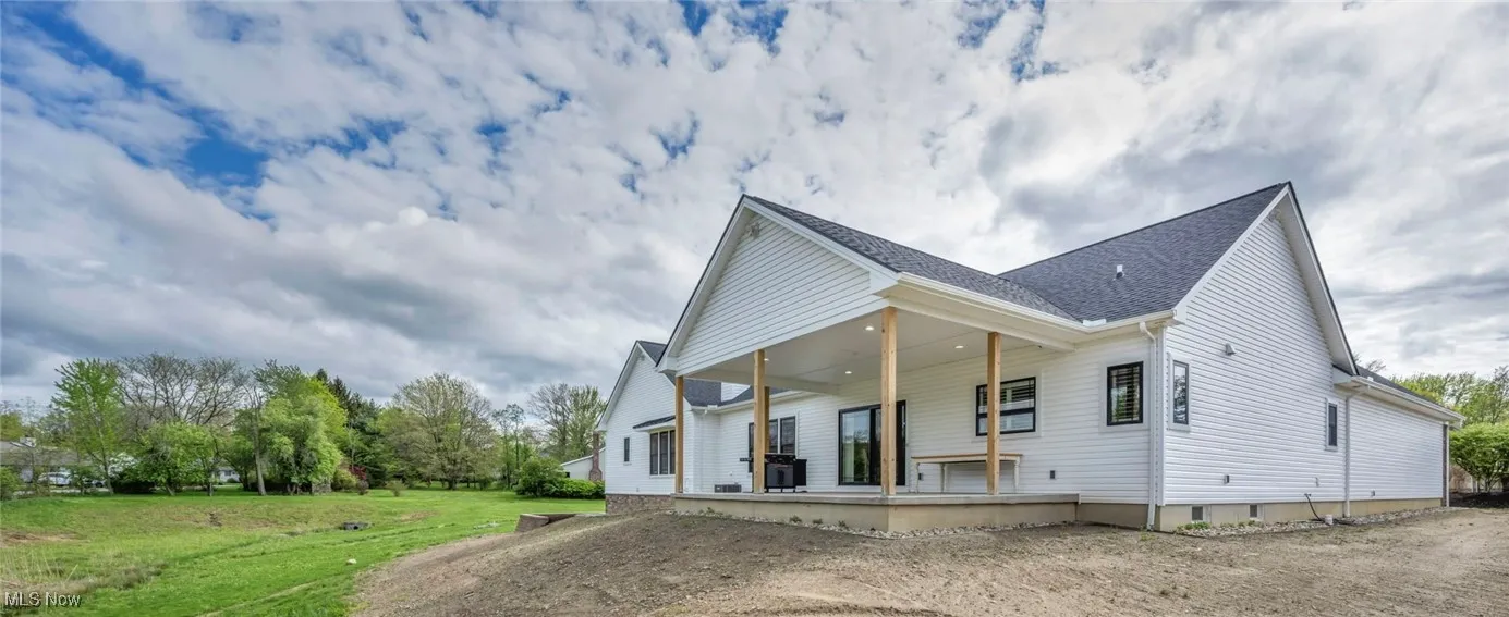 Back of property featuring a lawn, a porch, and a shingled roof