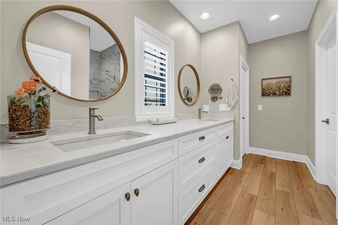 Full bathroom featuring hardwood / wood-style floors, double vanity, baseboards, and recessed lighting
