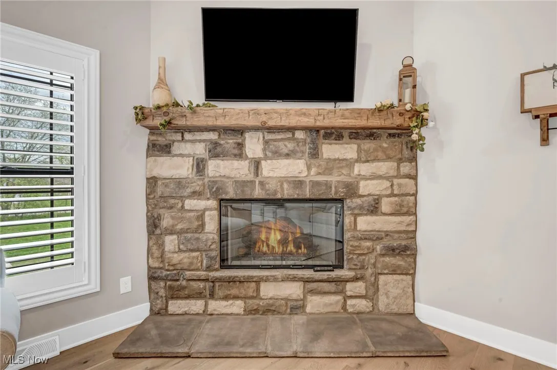 Detailed view of a stone fireplace, baseboards, and wood finished floors