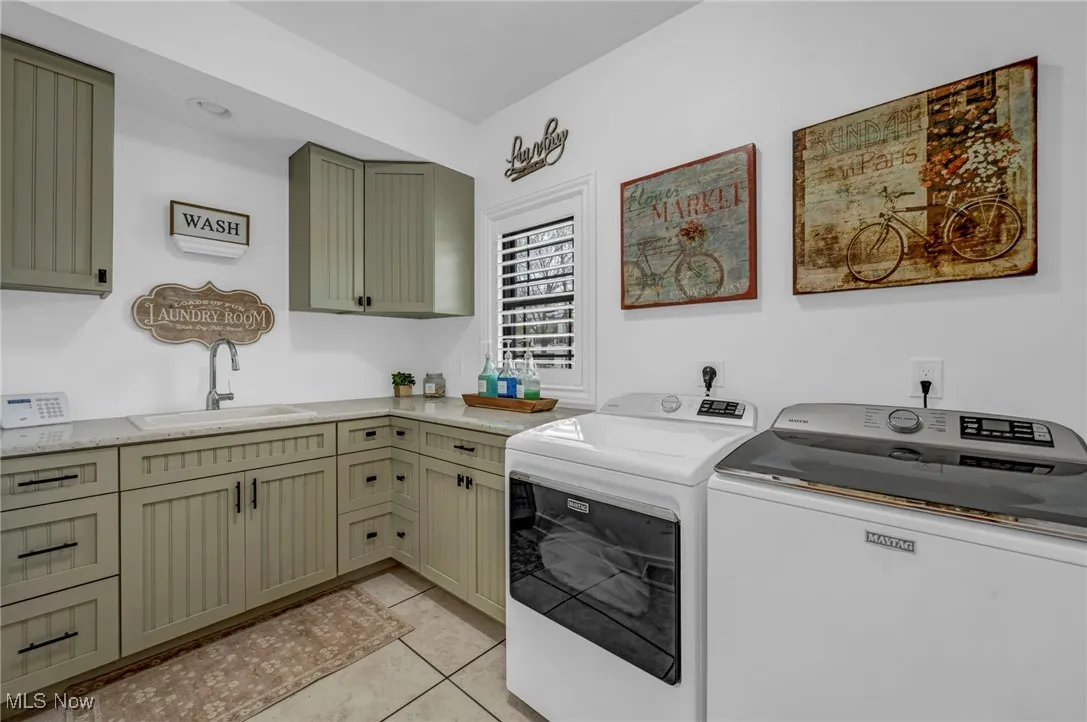 Laundry area featuring separate washer and dryer, cabinet space, and light tile patterned flooring