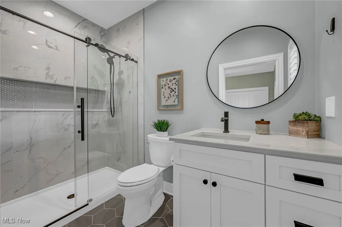 Bathroom featuring toilet, a marble finish shower, and vanity