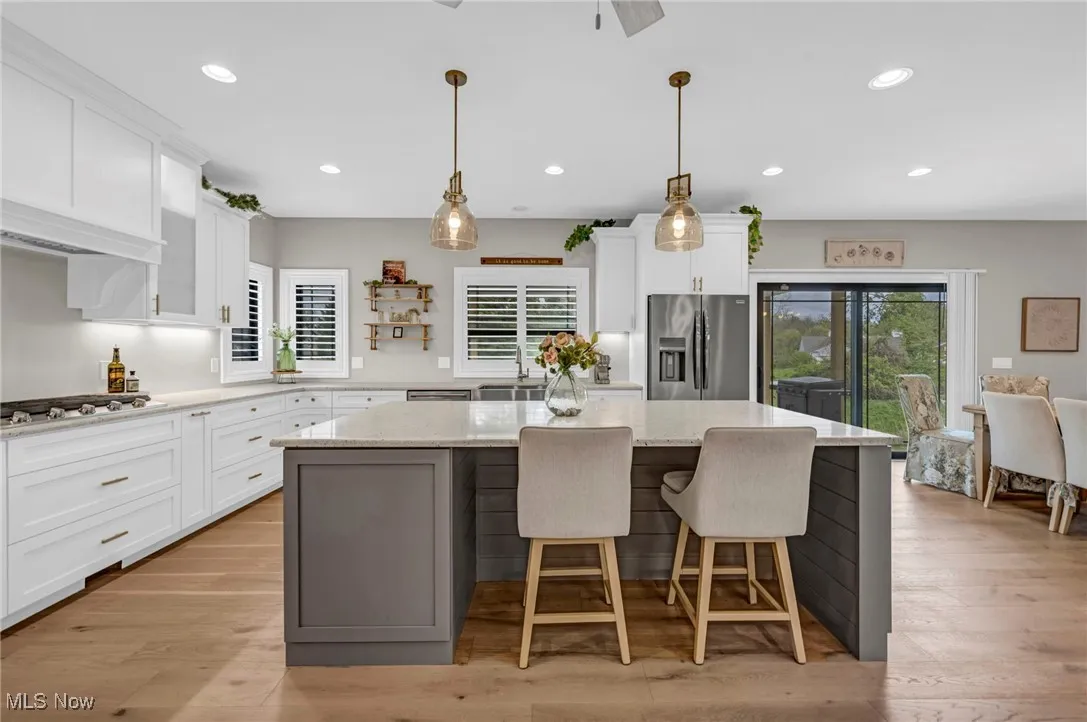 Kitchen featuring appliances with stainless steel finishes, a kitchen island, white cabinetry, light stone counters, and recessed lighting