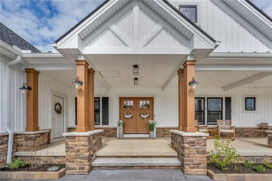 View of exterior entry featuring a porch, board and batten siding, and stone siding