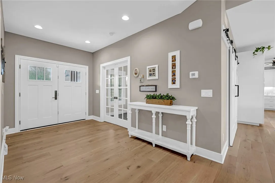 Foyer featuring a barn door, light wood finished floors, baseboards, recessed lighting, and french doors