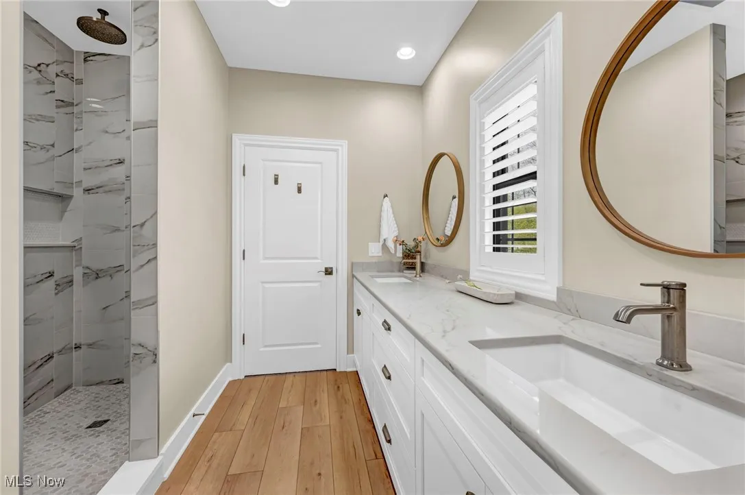 Full bath with wood-type flooring, walk in shower, recessed lighting, double vanity, and baseboards