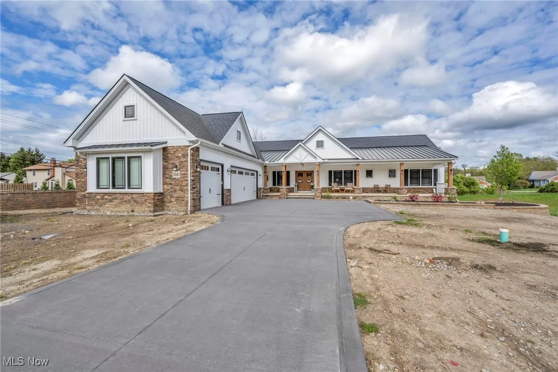 Modern inspired farmhouse featuring a porch, an attached garage, driveway, and a standing seam roof