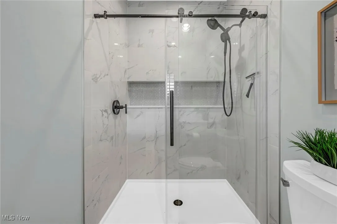 Full bath featuring toilet and a marble finish shower
