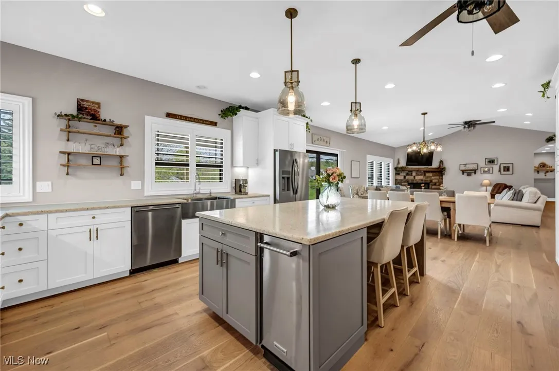 Kitchen featuring appliances with stainless steel finishes, a ceiling fan, healthy amount of natural light, open floor plan, and vaulted ceiling
