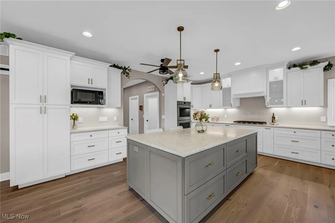 Kitchen featuring gray cabinetry, black microwave, ceiling fan, cooktop, and white cabinets