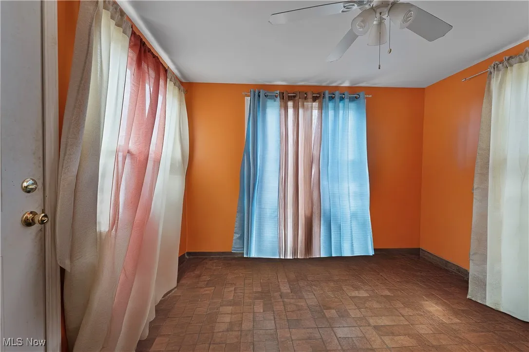 Empty room featuring ceiling fan and brick patterned flooring