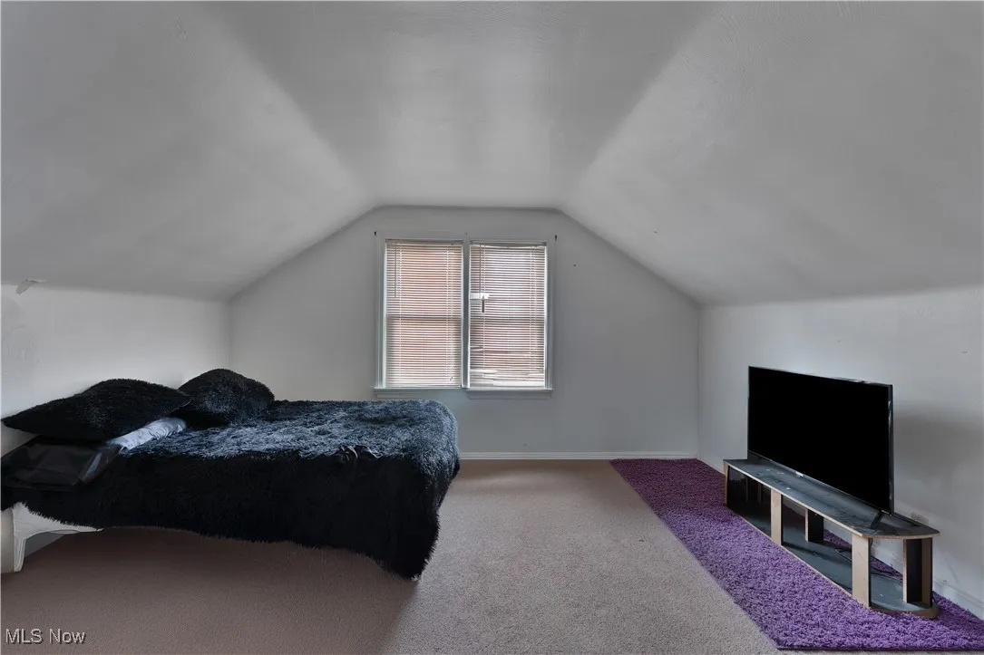 Bedroom with vaulted ceiling, carpet floors, and baseboards
