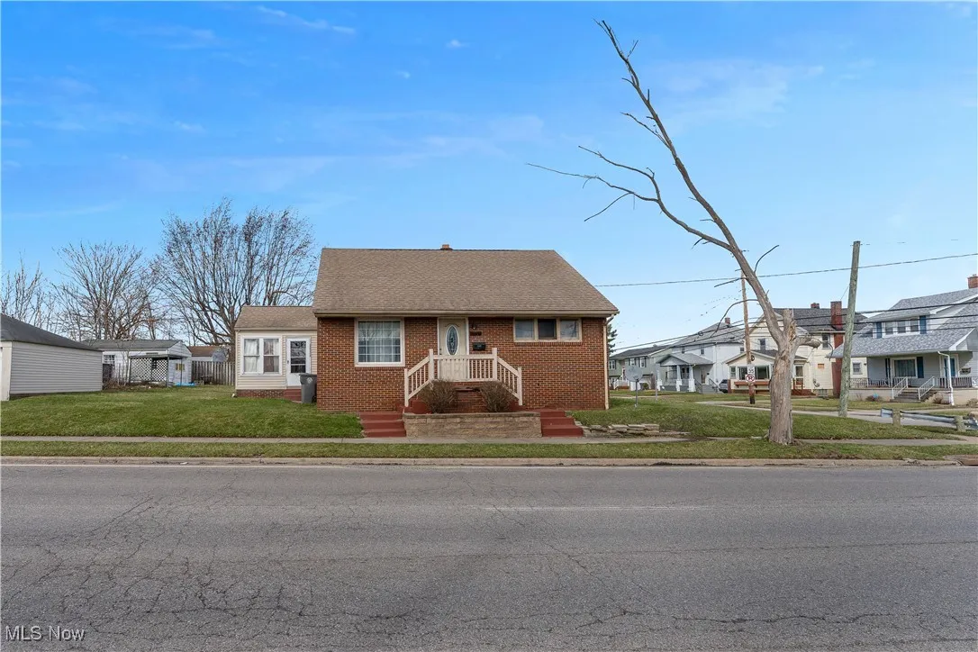 View of front facade featuring brick siding, a residential view, and a front yard
