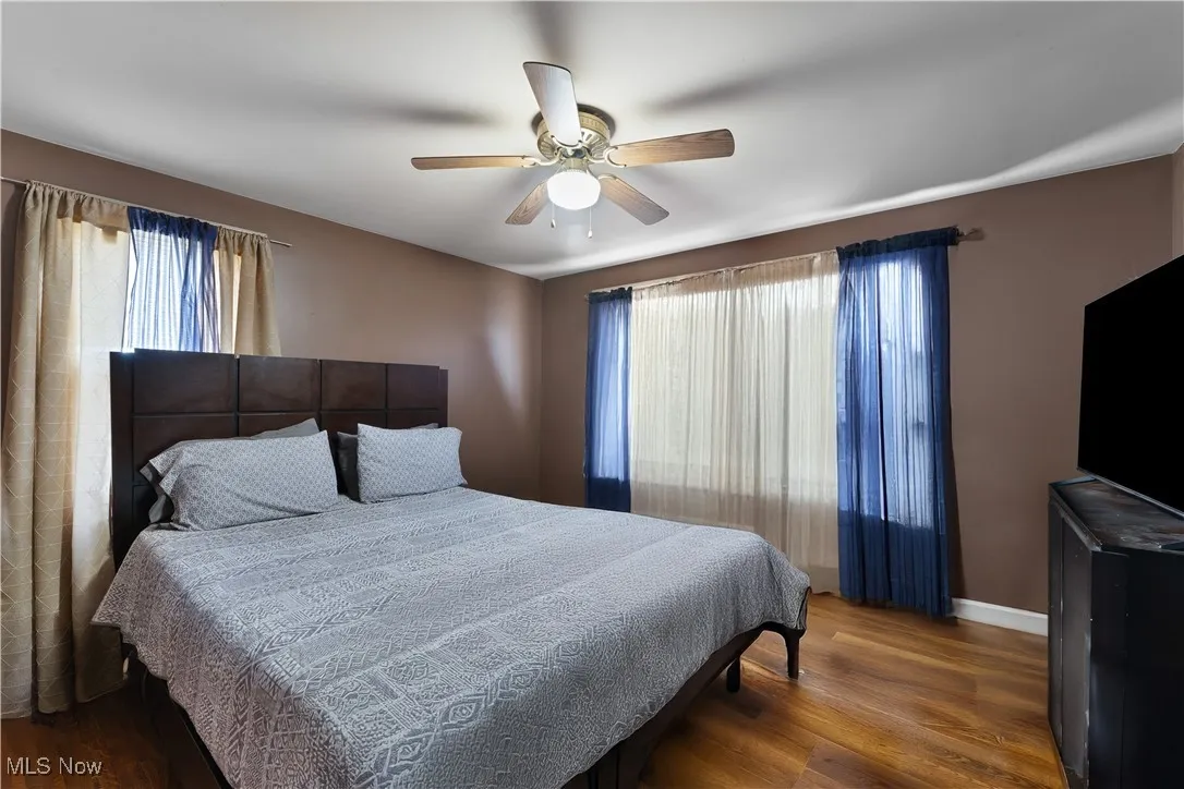Bedroom featuring multiple windows, wood finished floors, and a ceiling fan