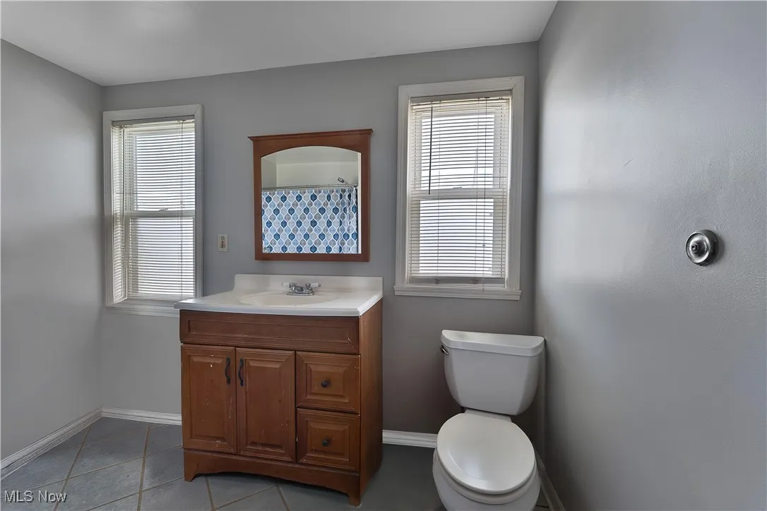 Bathroom with baseboards, vanity, toilet, tile patterned flooring, and a shower with shower curtain