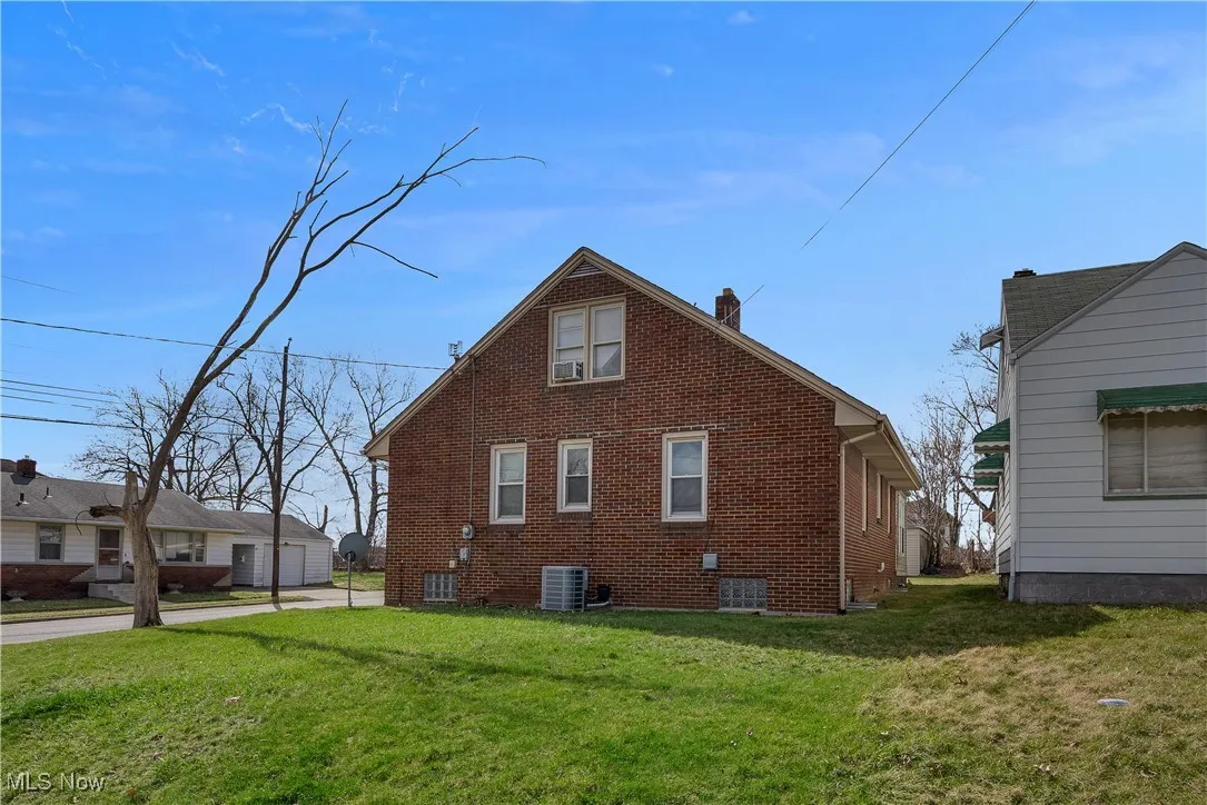 View of home's exterior featuring central air condition unit, a lawn, brick siding, and a chimney