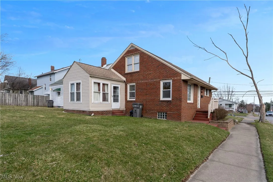 Rear view of property featuring entry steps, a chimney, and brick siding