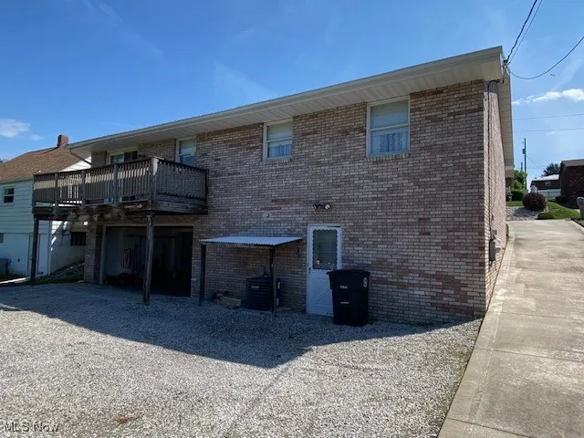 Rear view of house featuring brick siding, cooling unit, and a wooden deck