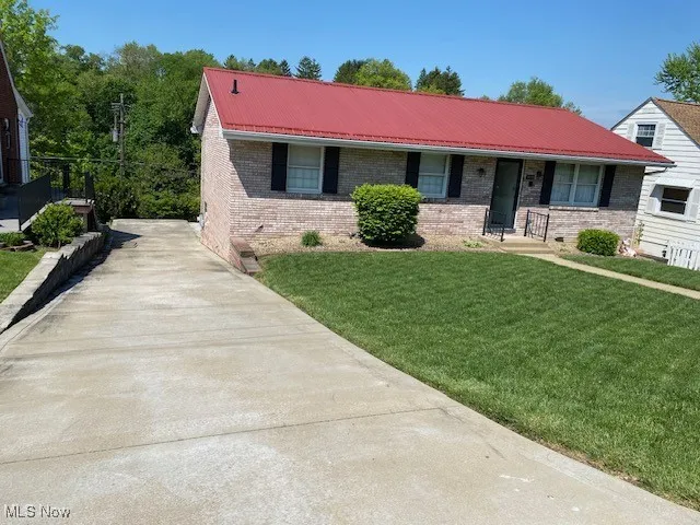 View of front facade featuring brick siding, a front lawn, and metal roof