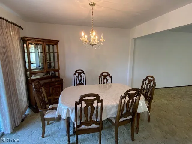 Carpeted dining area with a chandelier