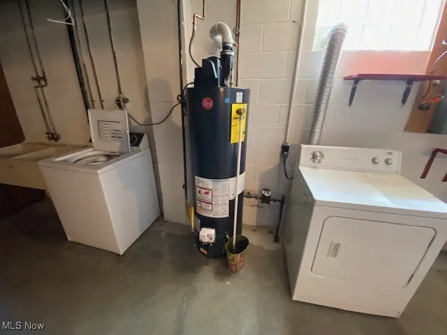Clothes washing area with gas water heater, concrete block wall, and washer and clothes dryer