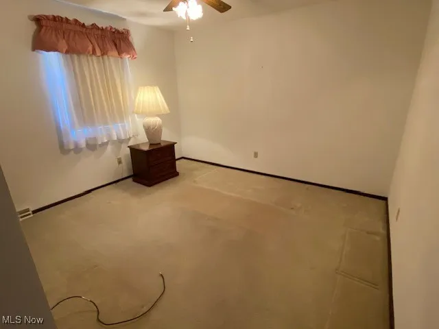 Spare room featuring ceiling fan, baseboards, and light colored carpet