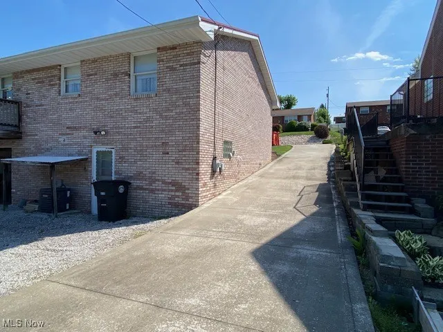 View of side of home featuring stairway and brick siding