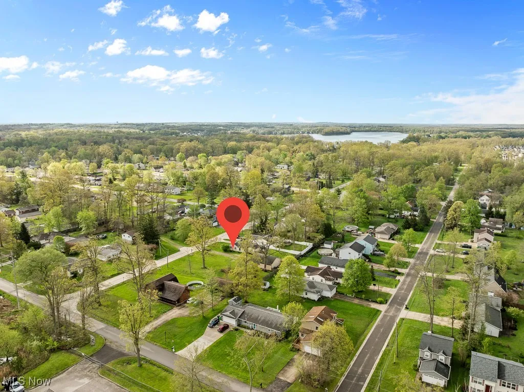 Aerial view of property's location featuring a nearby body of water, a heavily wooded area, and nearby suburban area