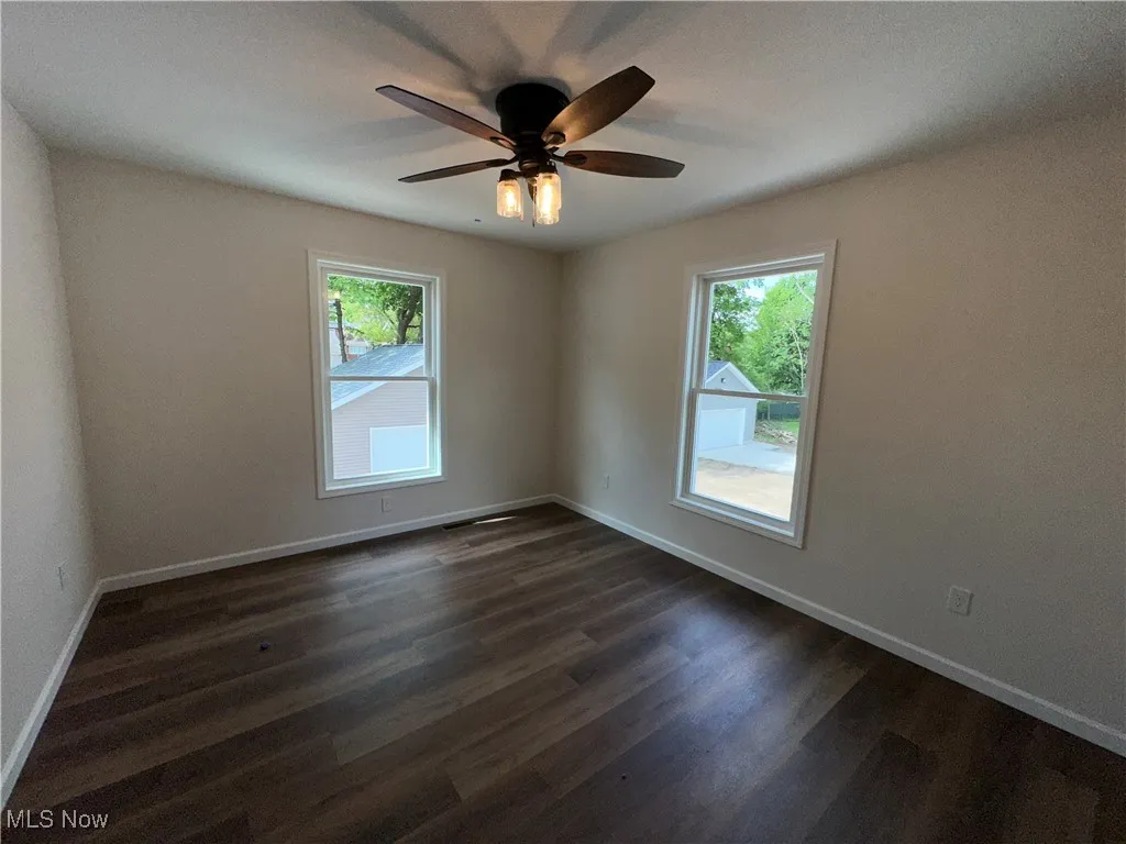 Bedroom with plenty of natural light, dark LVT floors, ceiling fan, and baseboards