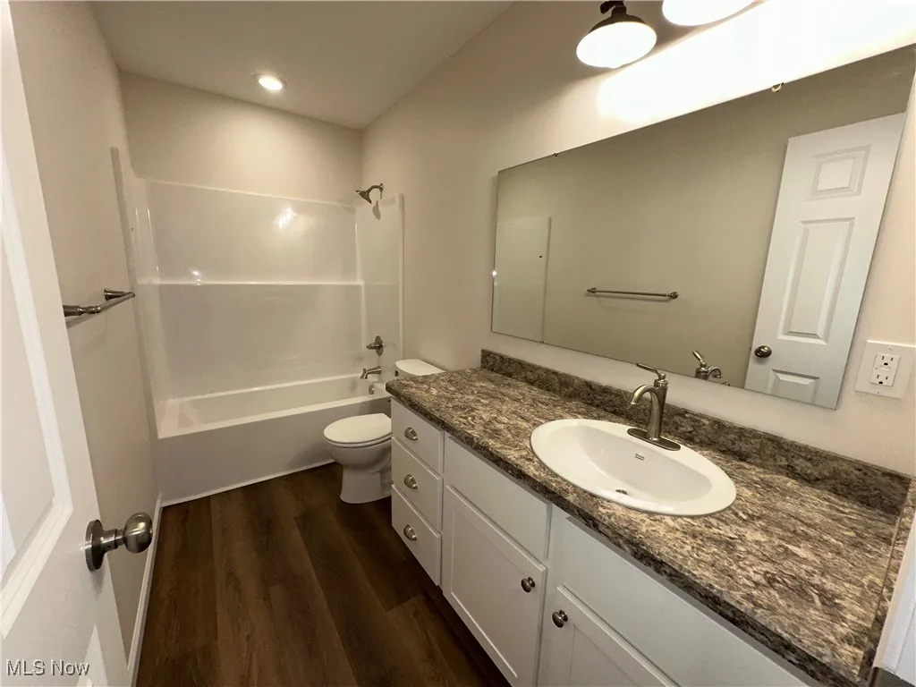 Bathroom with LVT floors, toilet, vanity, and tub / shower combination