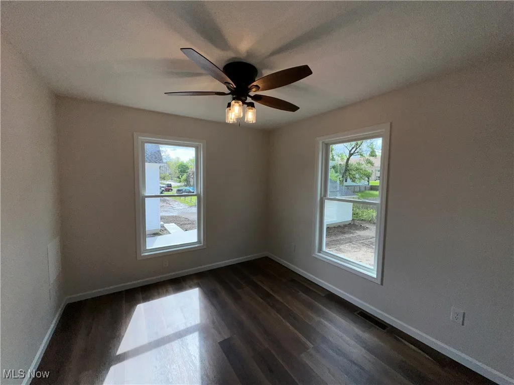 Unfurnished bedroom with dark LVT floors, baseboards, and ceiling fan