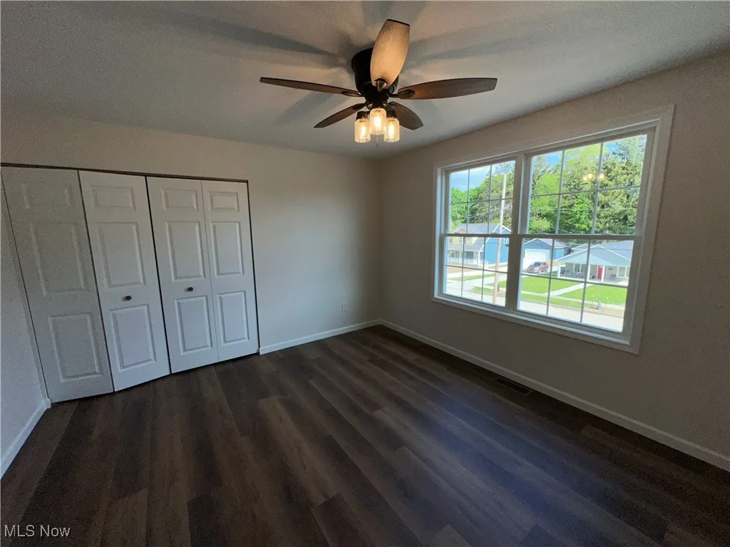 Unfurnished bedroom with baseboards, dark LVT flooring, a closet, and a ceiling fan