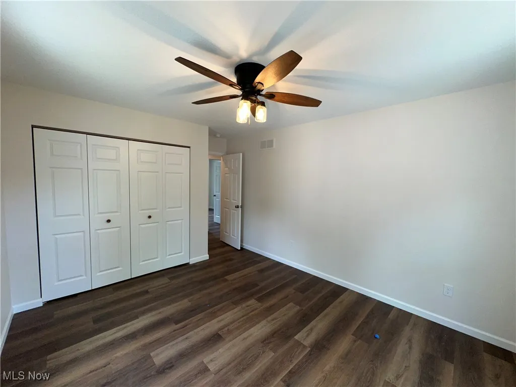 Unfurnished bedroom with baseboards, dark LVT floors, a closet, and ceiling fan