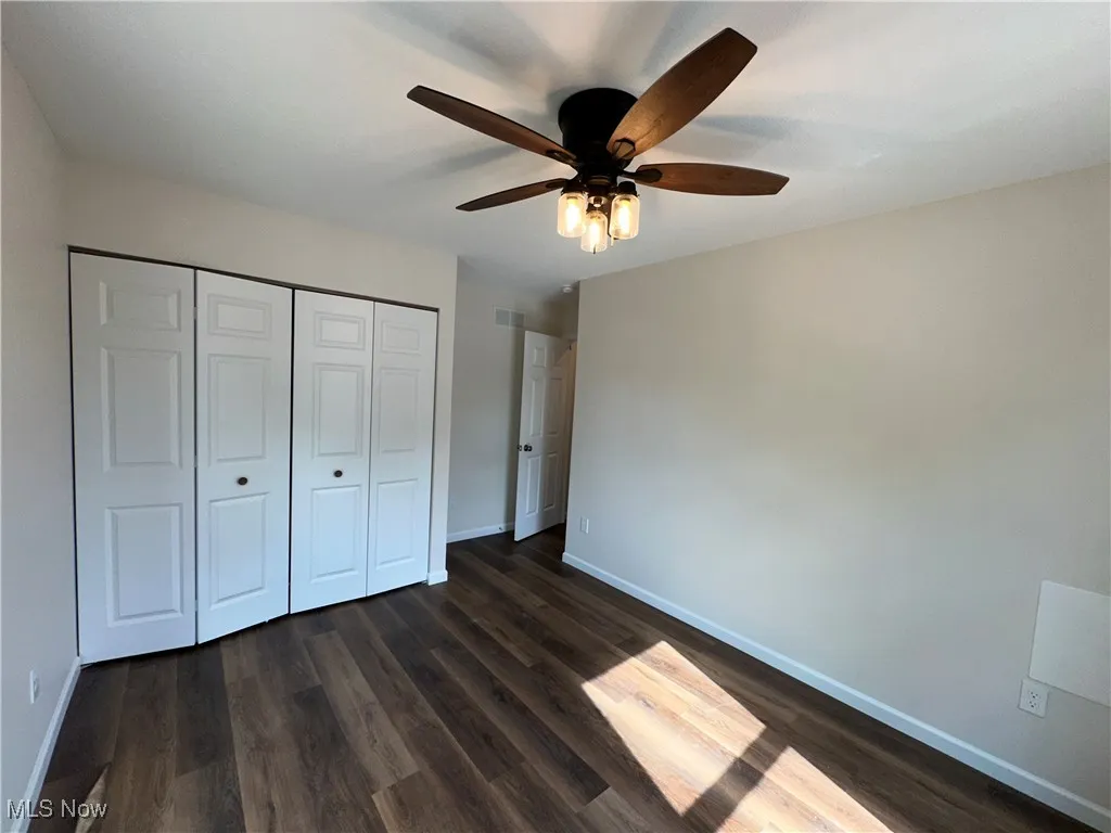 Unfurnished bedroom with baseboards, dark LVT flooring, a closet, and ceiling fan