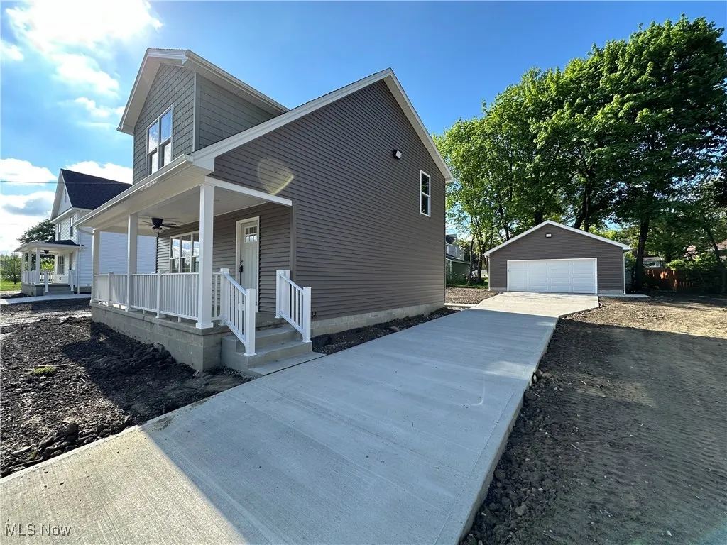 View of property exterior with covered porch with ceiling fan and a garage