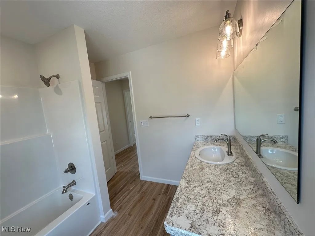 Full bathroom featuring shower / bathtub combination, vanity, LVT floors, and baseboards