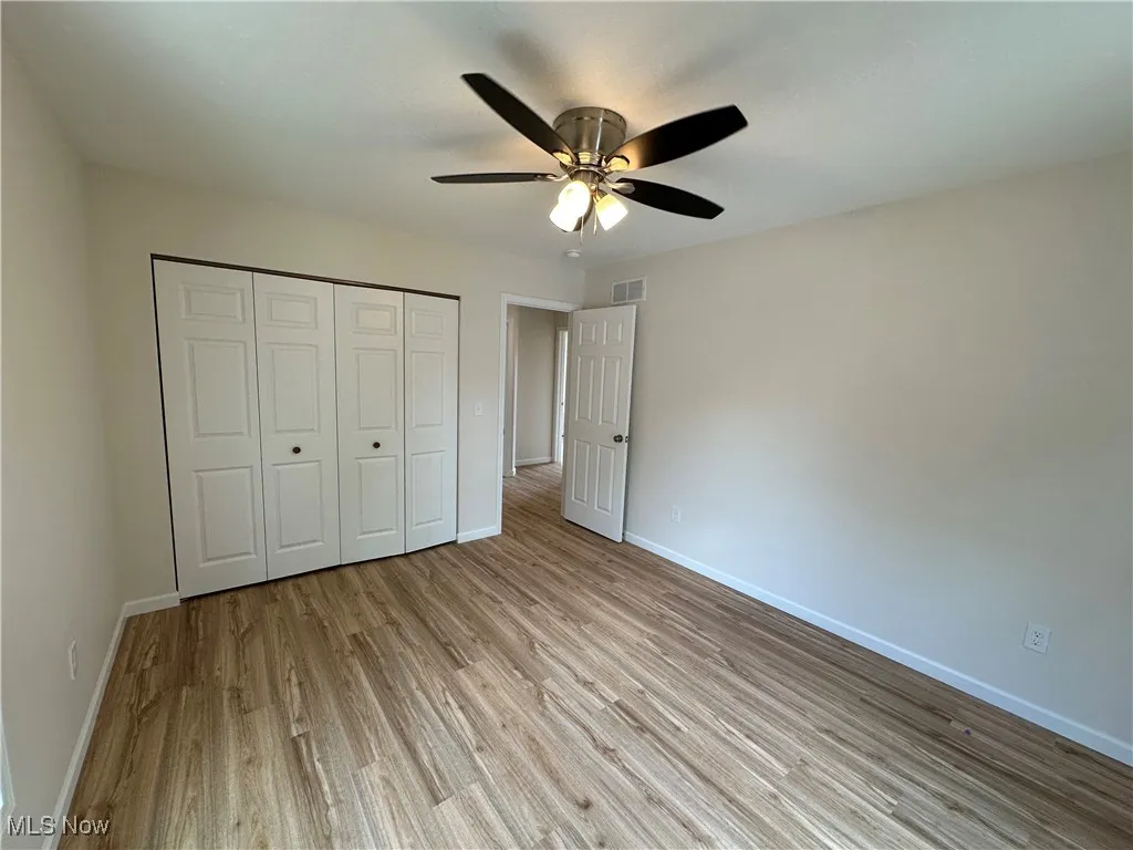Unfurnished bedroom featuring LVT floors, baseboards, a closet, and a ceiling fan