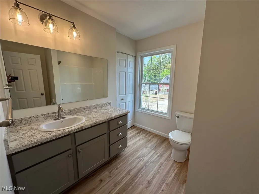 Full bath featuring LVT floors, toilet, vanity, baseboards, and a shower / bathtub combination