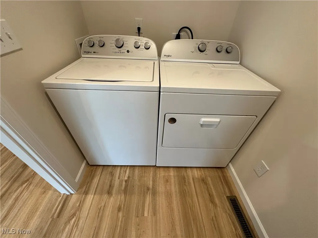 First floor laundry area with light LVT flooring, independent washer and dryer, and baseboards