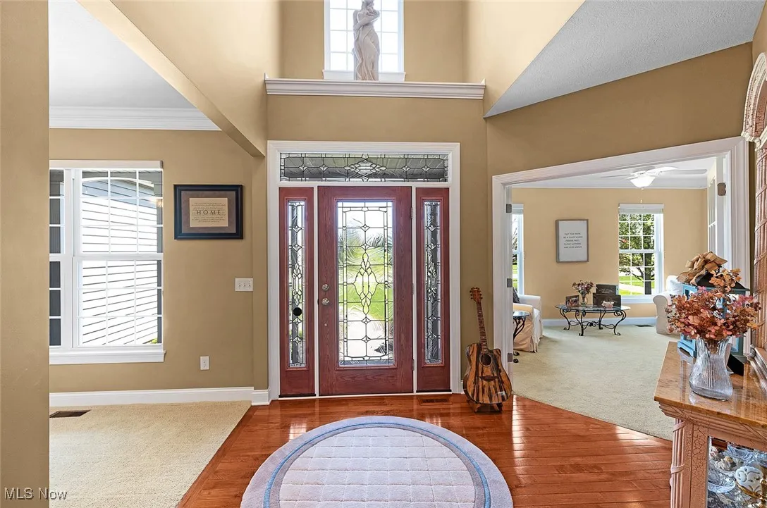 Foyer entrance with baseboards, carpet flooring, crown molding, wood finished floors, and a ceiling fan