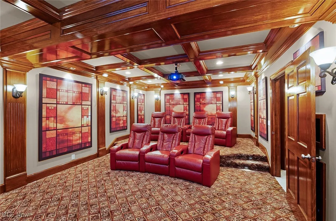 Carpeted cinema room featuring ornamental molding, baseboards, beamed ceiling, and coffered ceiling